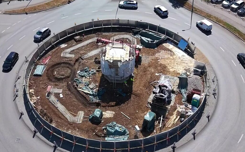 Pogled iz vazduha na kružni tok kod Lesnine sa ograđenim gradilištem spomenika